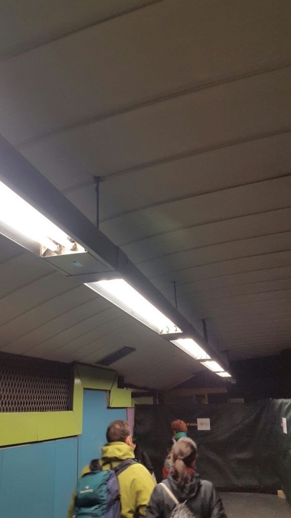 Un grupo de personas está de pie en una habitación oscura bajo una luz de techo.