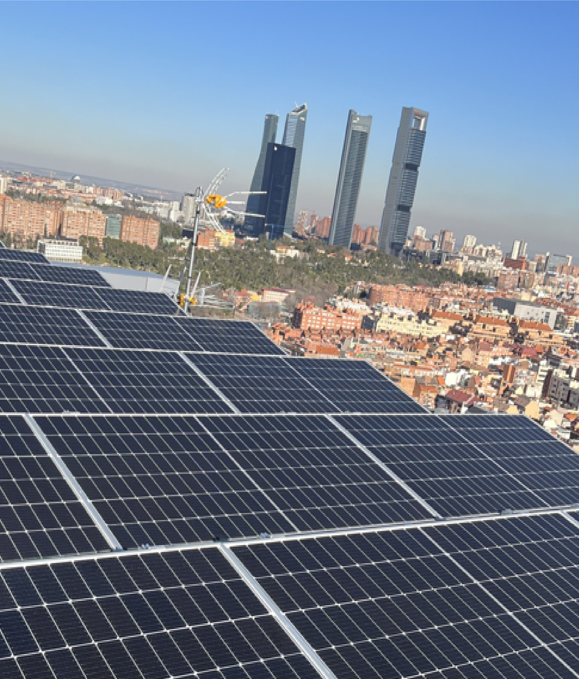 Una fila de paneles solares en la parte superior de un edificio con una ciudad al fondo.